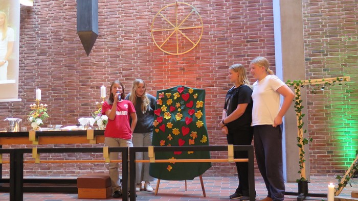 En gruppe af mennesker står i en kirke og ser på et stykke tæpper.