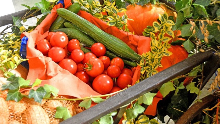 Frisch geerntetes Gemüse, darunter Tomaten, Gurken und Zucchini, in einer rustikalen Holzkiste.