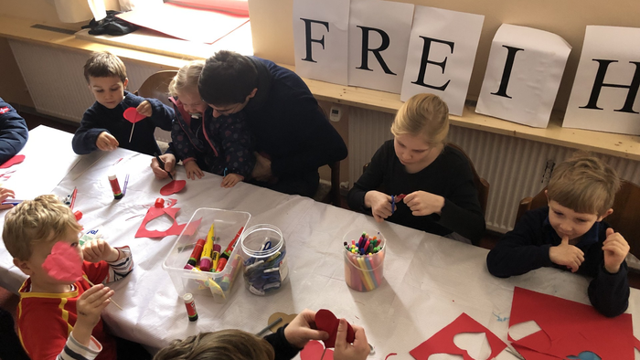 Kinder basteln unter Aufsicht in einem Klassenzimmer.
