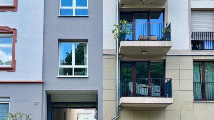 Das Bild zeigt einen Wohnblock mit Balkonen und einem Hinterhof.
