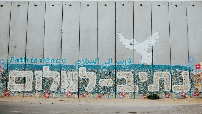 Graffiti an Betonmauer mit Friedensbotschaft in mehreren Sprachen