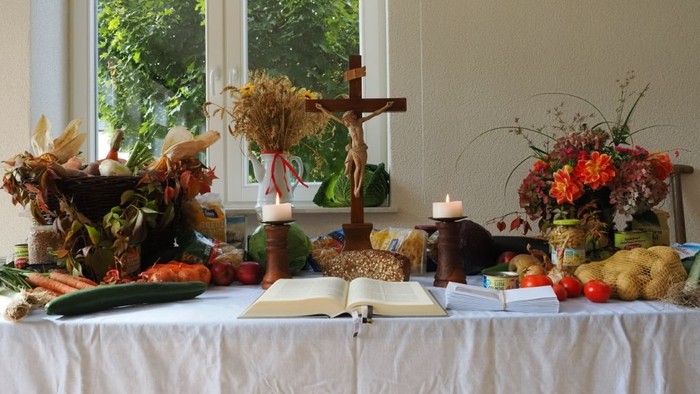 Tisch mit Herbstdekoration, darunter Blumen, Früchte und Kerzen.