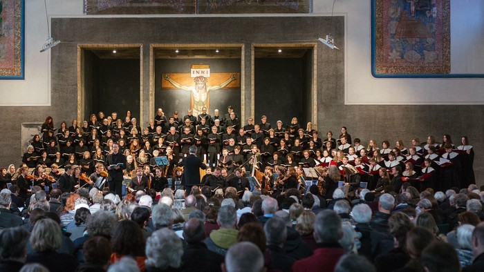 Große Menschenmenge in einer Kirche, viele sitzen, einige stehen, Chor singt vorne