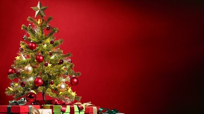 En juletree med pynt og several gaveboxer foran en rød baggrund