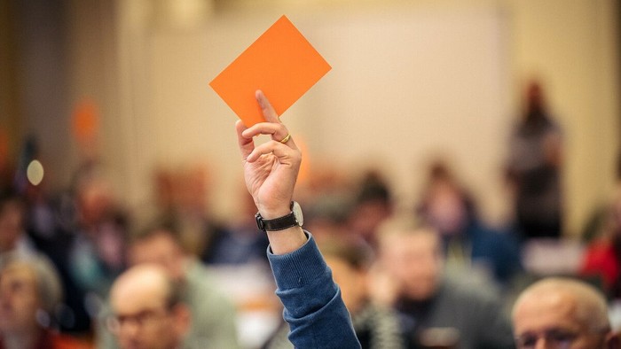 Eine Person hält in einem vollen Raum eine rote Karte hoch.