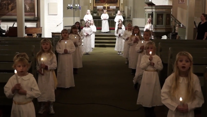 Børn i hvide klerer med lys i kirke