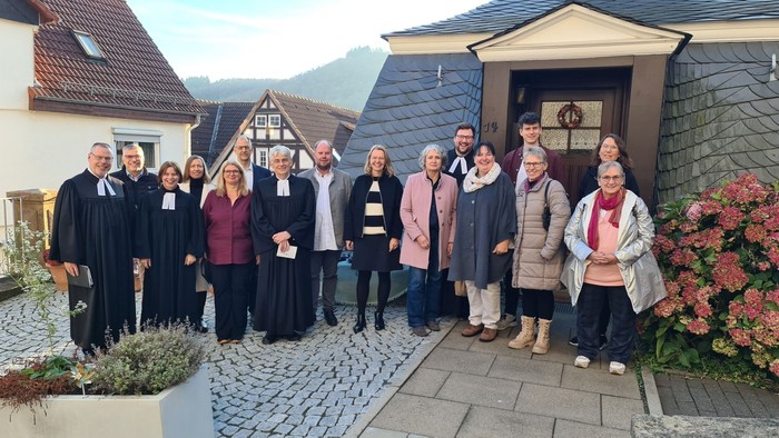 Gruppe von Menschen in feierlicher Kleidung vor altem Haus
