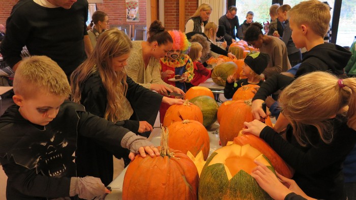 Børn og voksne laver halloween-dekorationer af pærer.