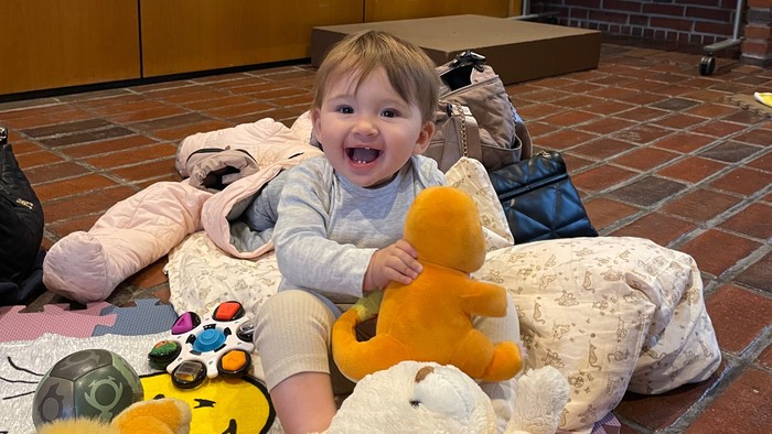 Barn sidder med bamser på legetæppe.