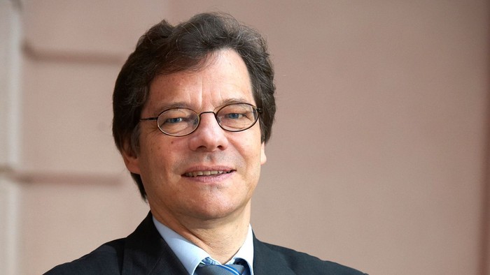 Mann mit Brille und Krawatte lächelt in die Kamera
