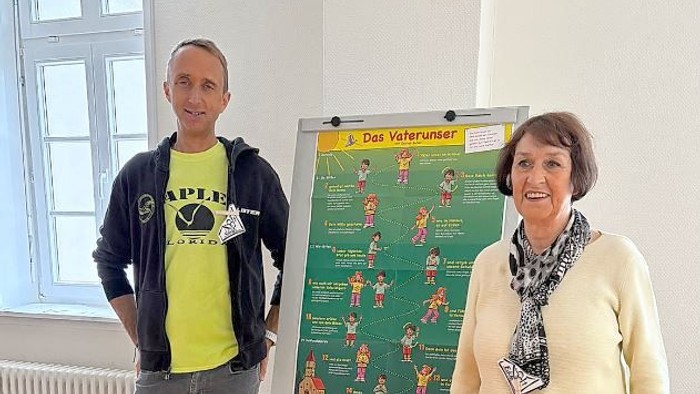 Zwei Personen stehen in der Nähe eines Posters mit Übungsanweisungen.