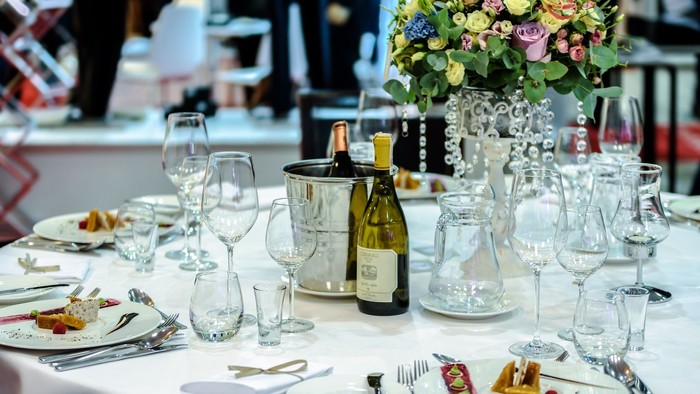 Indretning til festlig måltid med blomster, vin og glas.