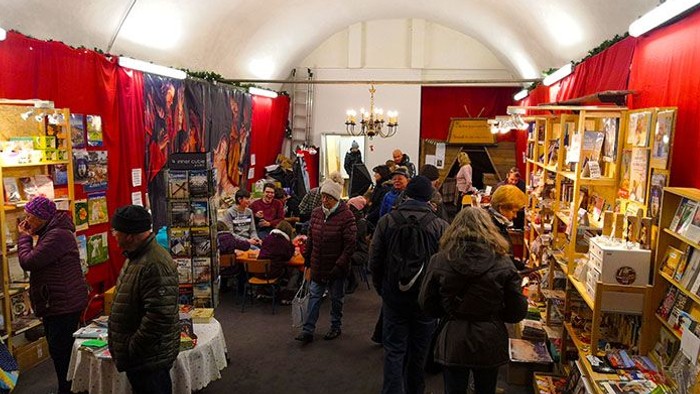 Ein belebter Marktraum mit Menschen, die an verschiedenen Ständen mit Büchern und Kunstwerken stöbern.