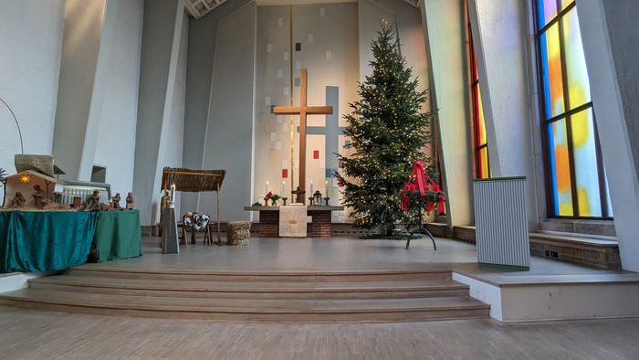 In der Kirche steht ein geschmückter Weihnachtsbaum vor dem Altar.