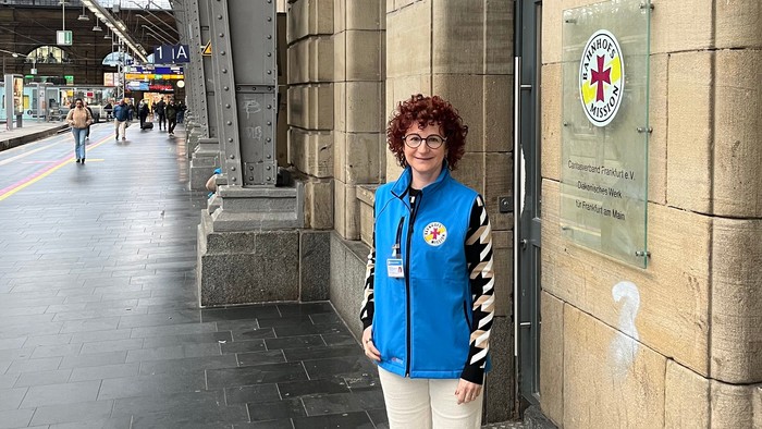 Frau steht vor einem Gebäude mit einem gelben und roten Schild.