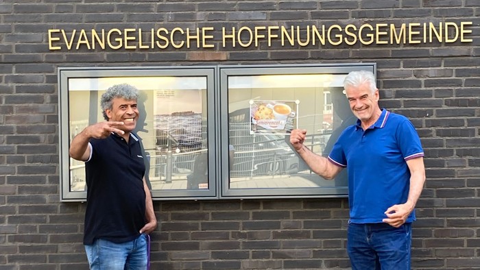 Zwei Männer stehen vor einem Ziegelgebäude mit Bildern