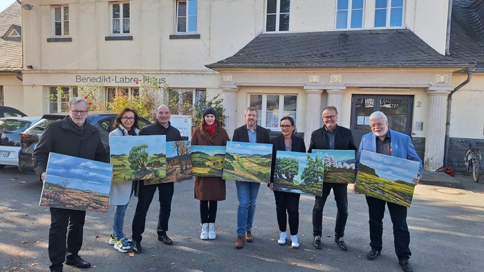 Eine Gruppe von Menschen hält Gemälde vor einem Gebäude