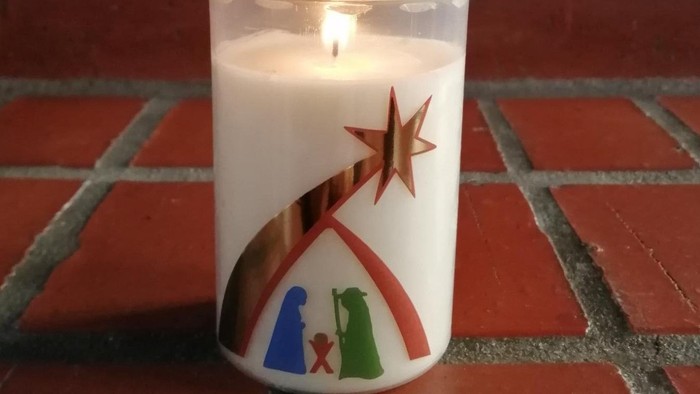 Weiße Kerze mit goldenen Stern und Heiligen Drei Königen auf rotem Fliesenboden