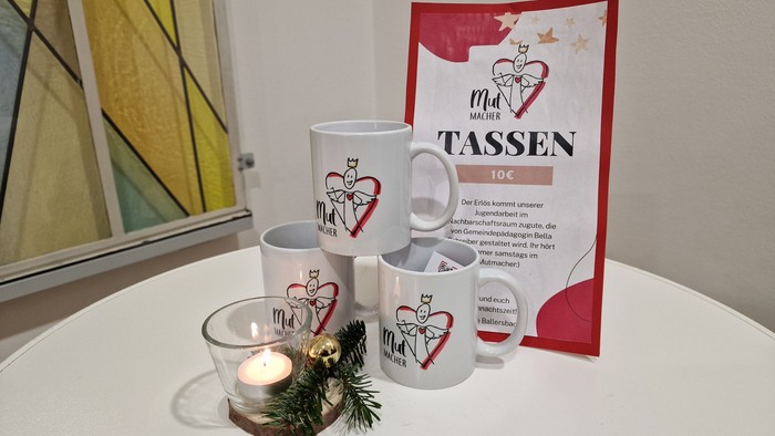 Weiße Tassen mit Herzdesign und Kerze auf Tisch