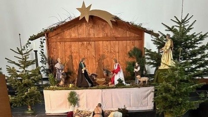 Eine Weihnachtskrippe mit Holzfiguren und Tannenbäumen.