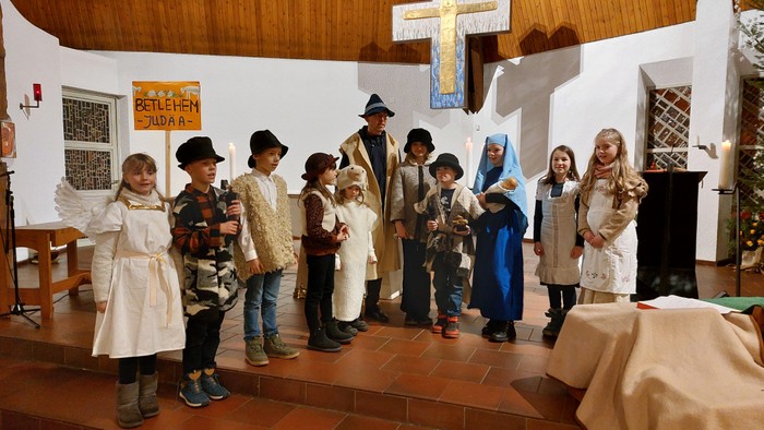 Kinder in Kirchenkleidung posieren vor Kreuz