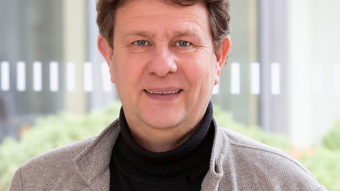 Ein Mann mit grauen Haaren lächelt in die Kamera.