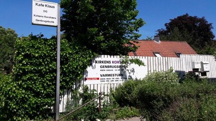 En hvid bygning med rødt tag og et skilt der siger