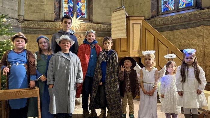 Kinder in Kostümen posieren für ein Gruppenfoto in einer Kirche.