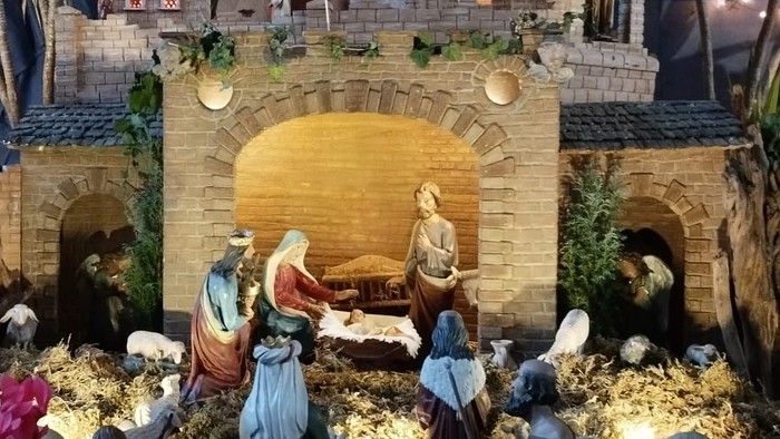 Eine detaillierte Weihnachtskrippe mit Figuren und einer Weihnachtsbeleuchtung.