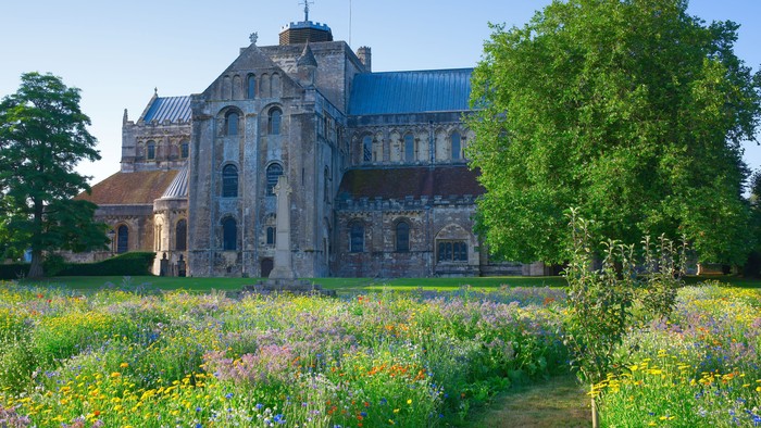 Large historic building surrounded by lush greenery and wildflowers.