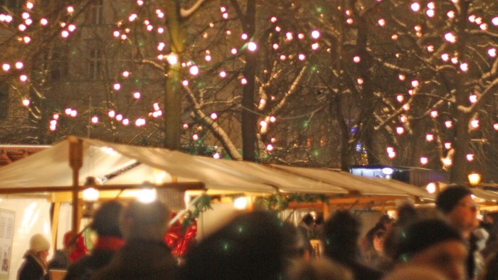 Weihnachtsmarkt bei Nacht mit Lichtern und Menschen
