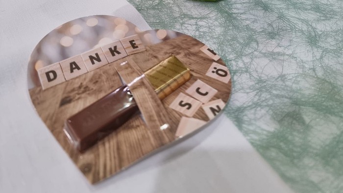 Ein Blumenstrauß in einer grünen Vase auf einem Tisch mit einer Dankeskarte