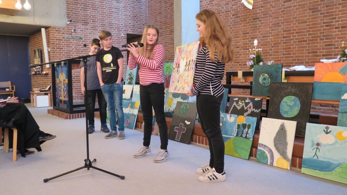 En gruppe unge præsenterer deres malerier i et atelier