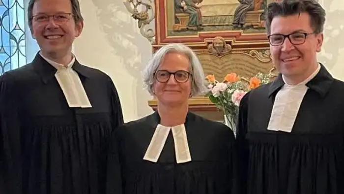 Prädikantin Heike Spielmann zusammen mit Superintendent Waskönig und Pfarrer Hick in der Dahler Dorfkirche vor dem Altar.