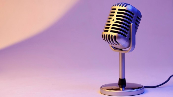 Ein Mikrofon auf einem Ständer vor lila Hintergrund