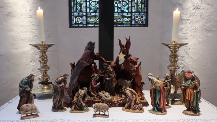 Die Szene zeigt eine Krippe mit verschiedenen Figuren und Kerzen.