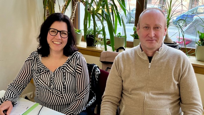 Ein Mann und eine Frau sitzen an einem Tisch mit Laptop und Papieren.