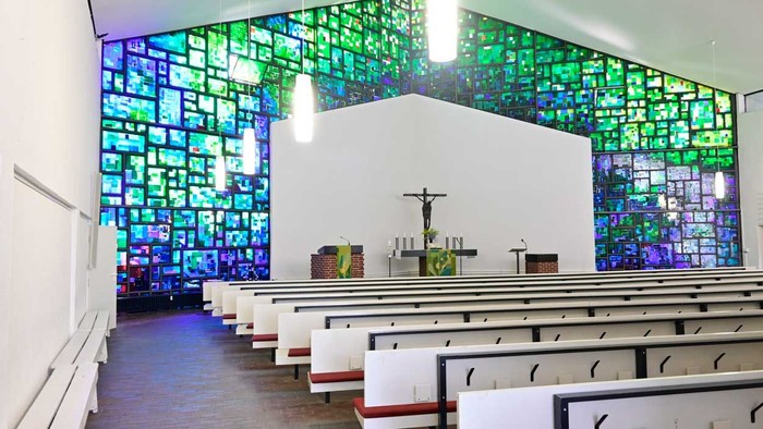 Die Kirche hat bunte Glasfenster und weiße Bänke