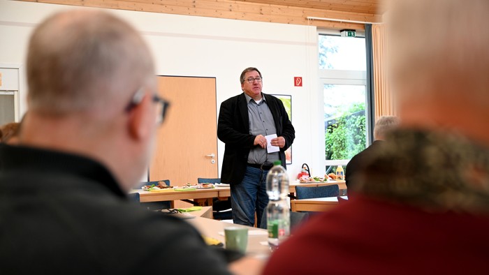 Ein Mann steht vor einem Publikum und hält eine Präsentation.