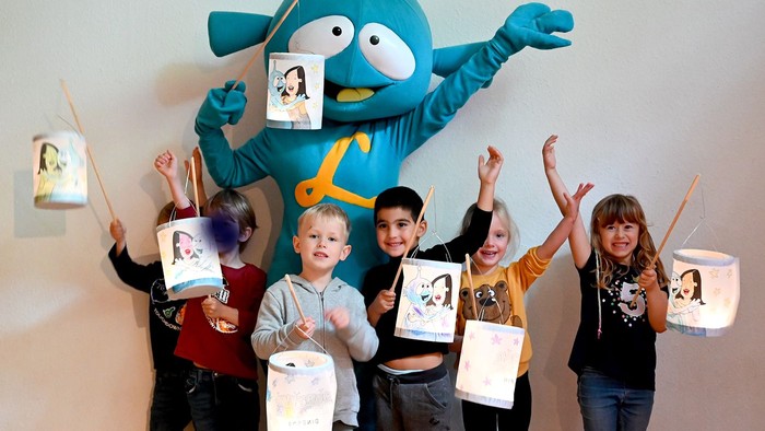 Kinder posieren mit blauen Maskottchen und Laternen