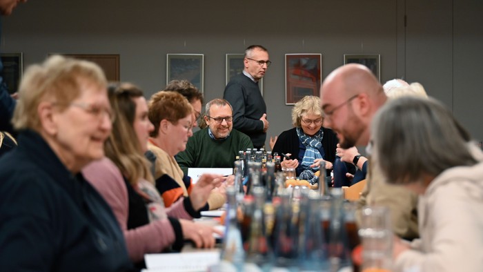 Eine Gruppe von Menschen sitzt an einem Tisch und ist in ein Gespräch vertieft.