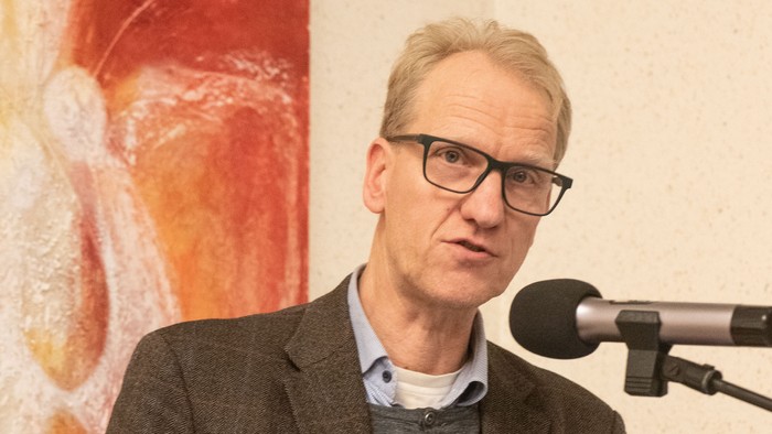 Mann spricht hinter Pult mit Mikrofon