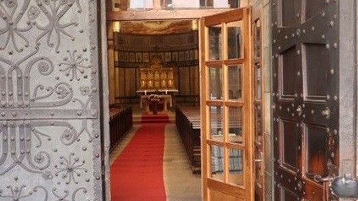 Offene Holztür mit rotem Teppich dahinter