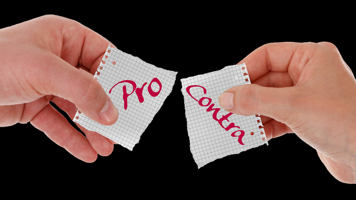 Zwei Hände halten und trennen „Pro“- und „Contra“-Karten auf Millimeterpapier.