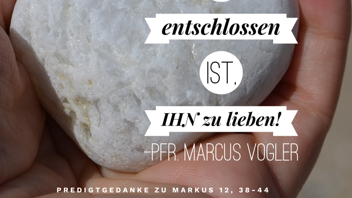 Hand hält einen herzförmigen Stein mit deutschem Text.