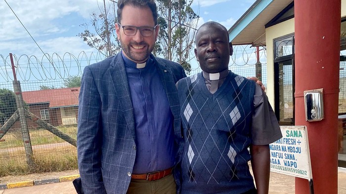 Zwei Männer in kirchlicher Kleidung stehen vor einem Gebäude