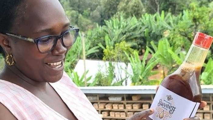Frau hält eine Flasche Wein auf einem Balkon mit Blick auf tropische Pflanzen.