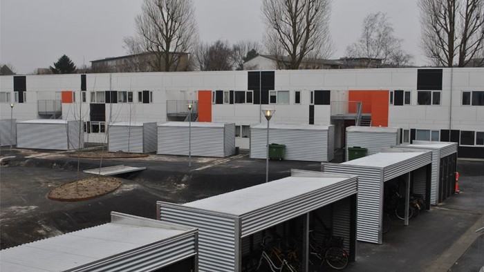 Industribygning med orange og sorte detaljer og flere garages.