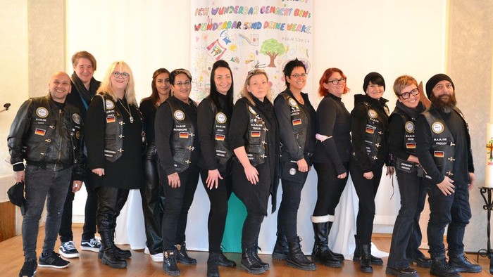 Gruppe von Menschen, die gemeinsam posieren und Lederjacken sowie Westen mit Aufnähern tragen.