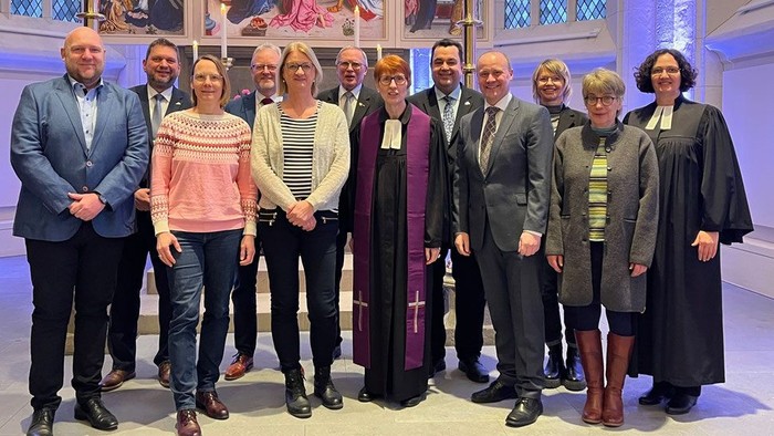 Gruppe von Personen, die vor einem religiösen Kunstwerk posieren